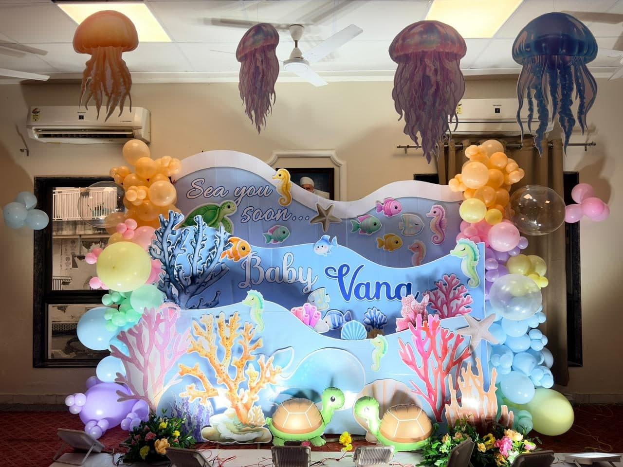 Under-the-sea baby shower backdrop with jellyfish, coral and pastel balloons