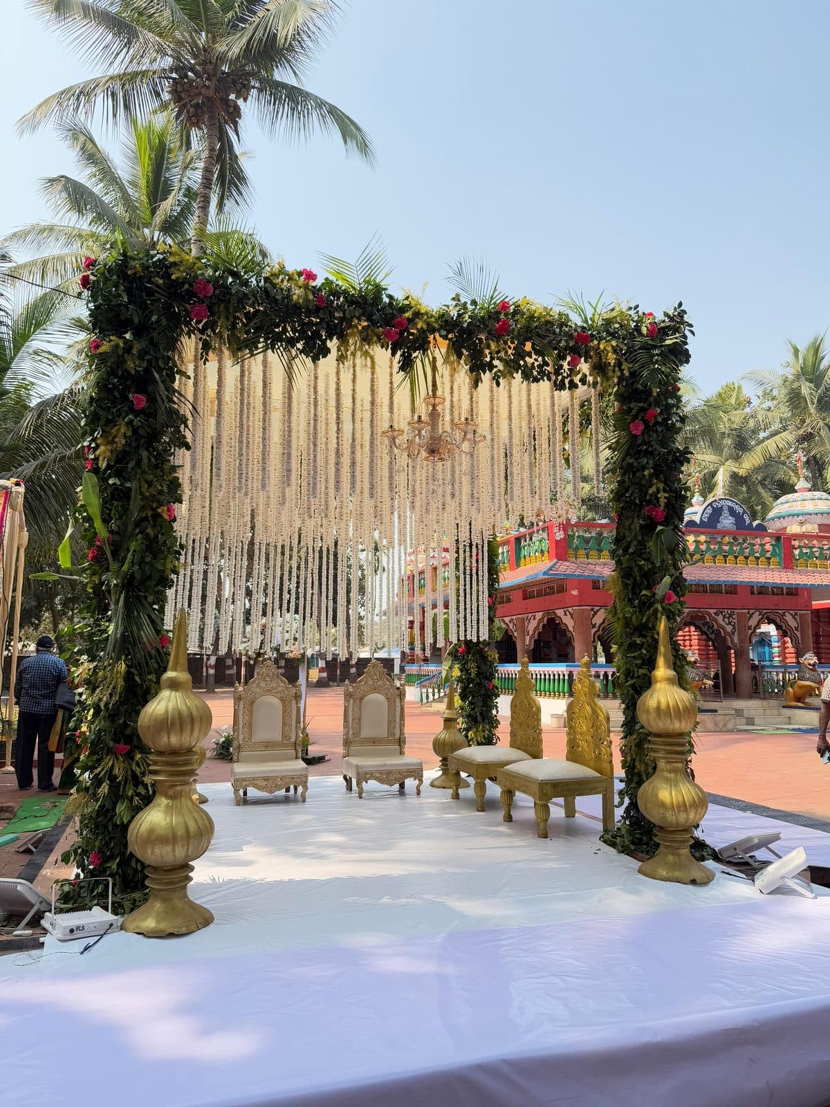 Wide view of a floral wedding mandap with gold seating